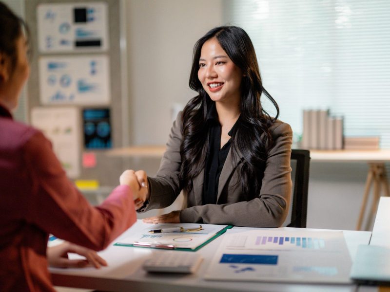 Professional women concluding successful negotiation, exchanging handshake in corporate workspace